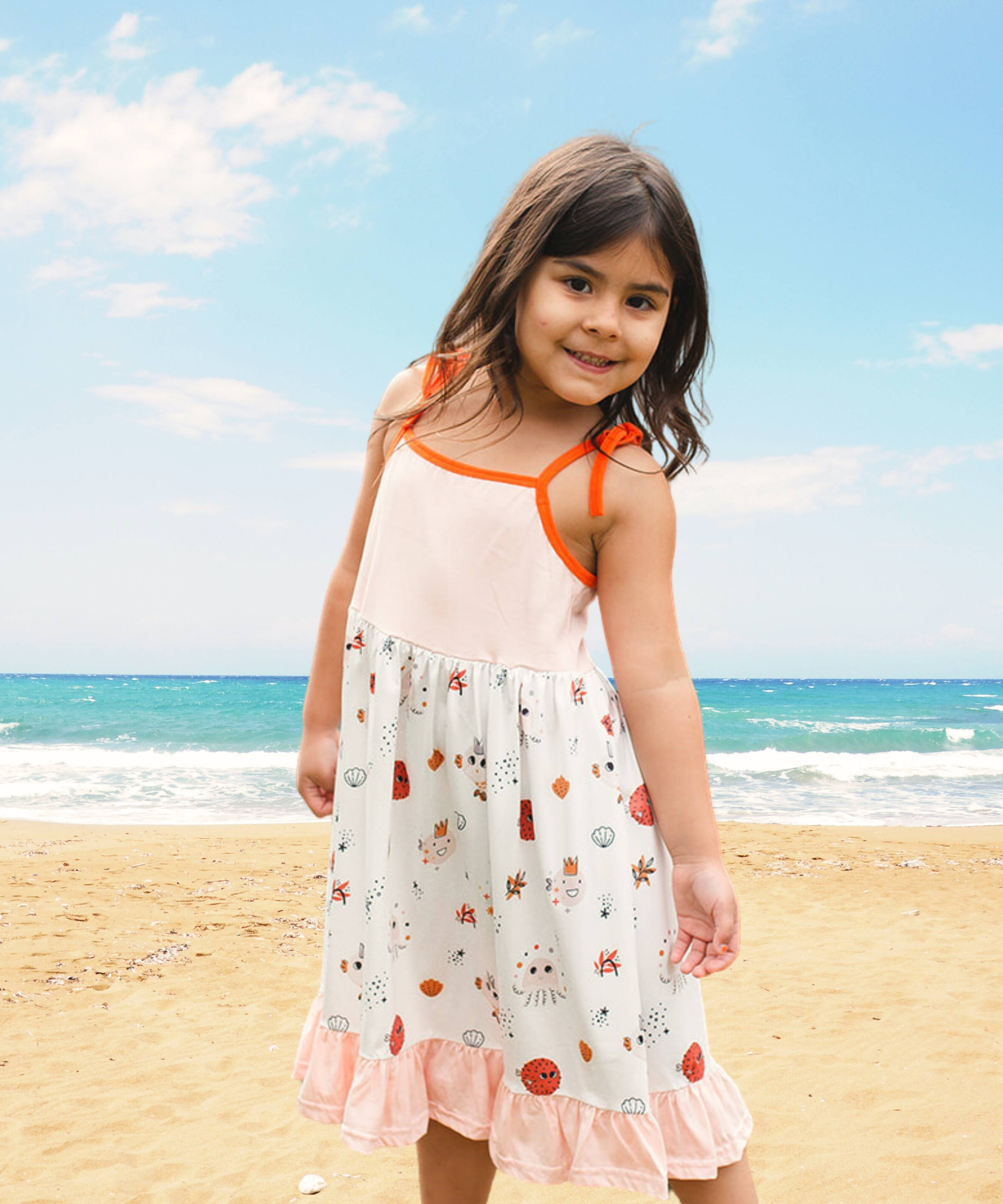 Vestido de verano para playa color rosa suave con capas de volantes en la falda y detalles de criaturas marinas en naranja y marrón