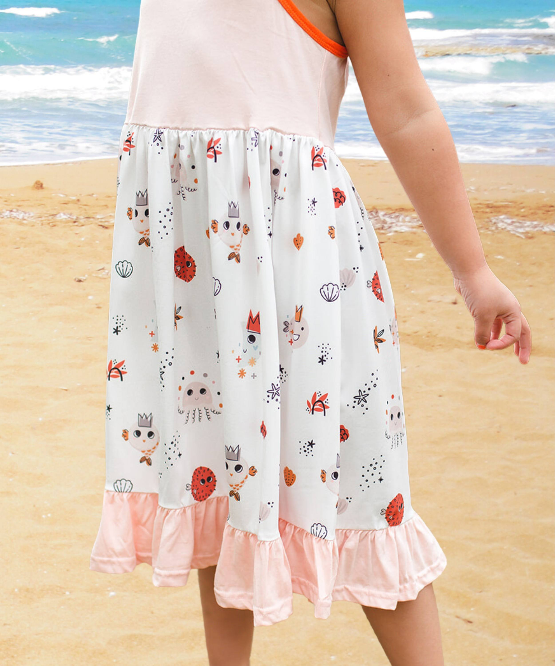 Vestido de verano para playa color rosa suave con capas de volantes en la falda y detalles de criaturas marinas en naranja y marrón