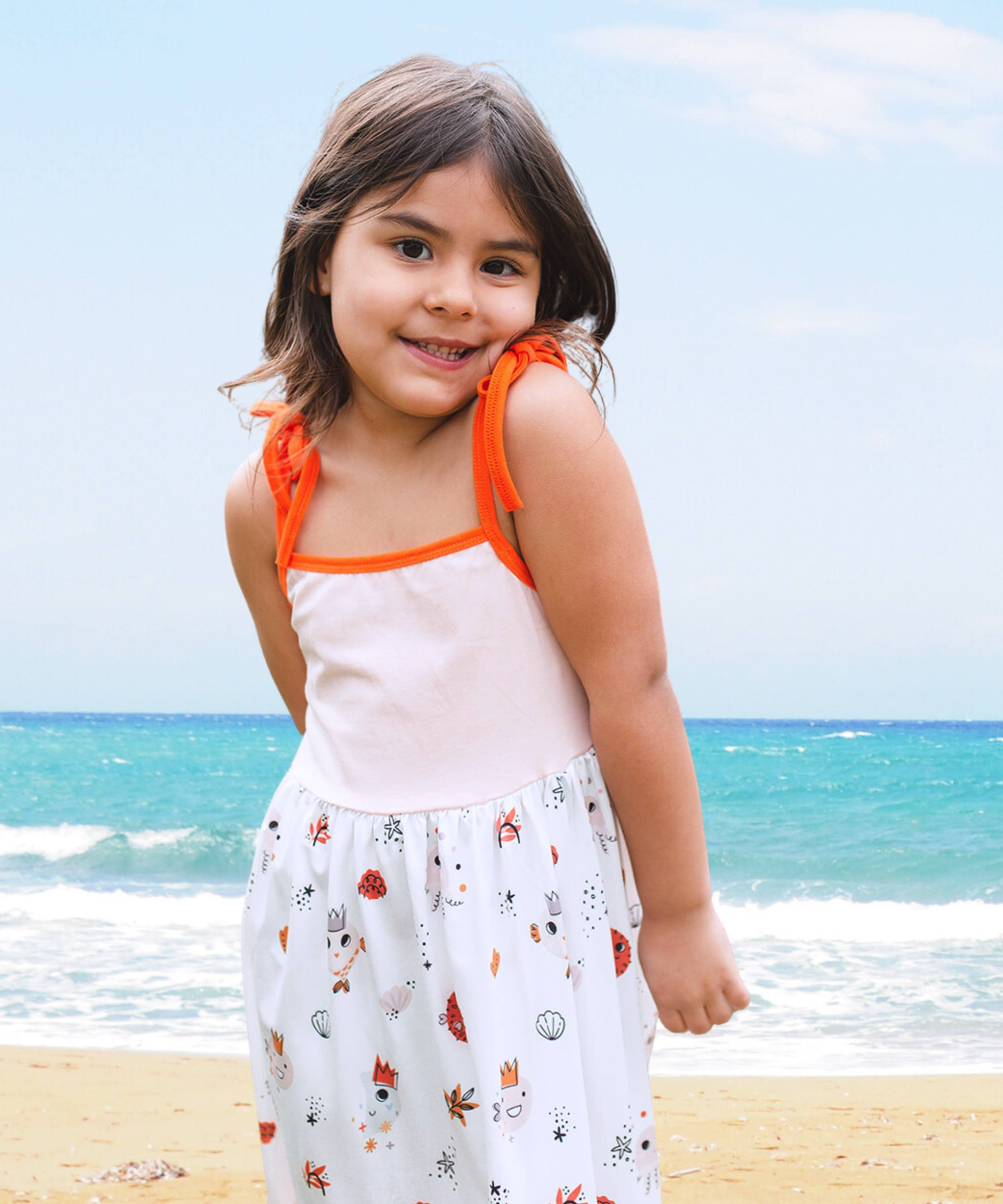 Vestido de verano para playa color rosa suave con capas de volantes en la falda y detalles de criaturas marinas en naranja y marrón